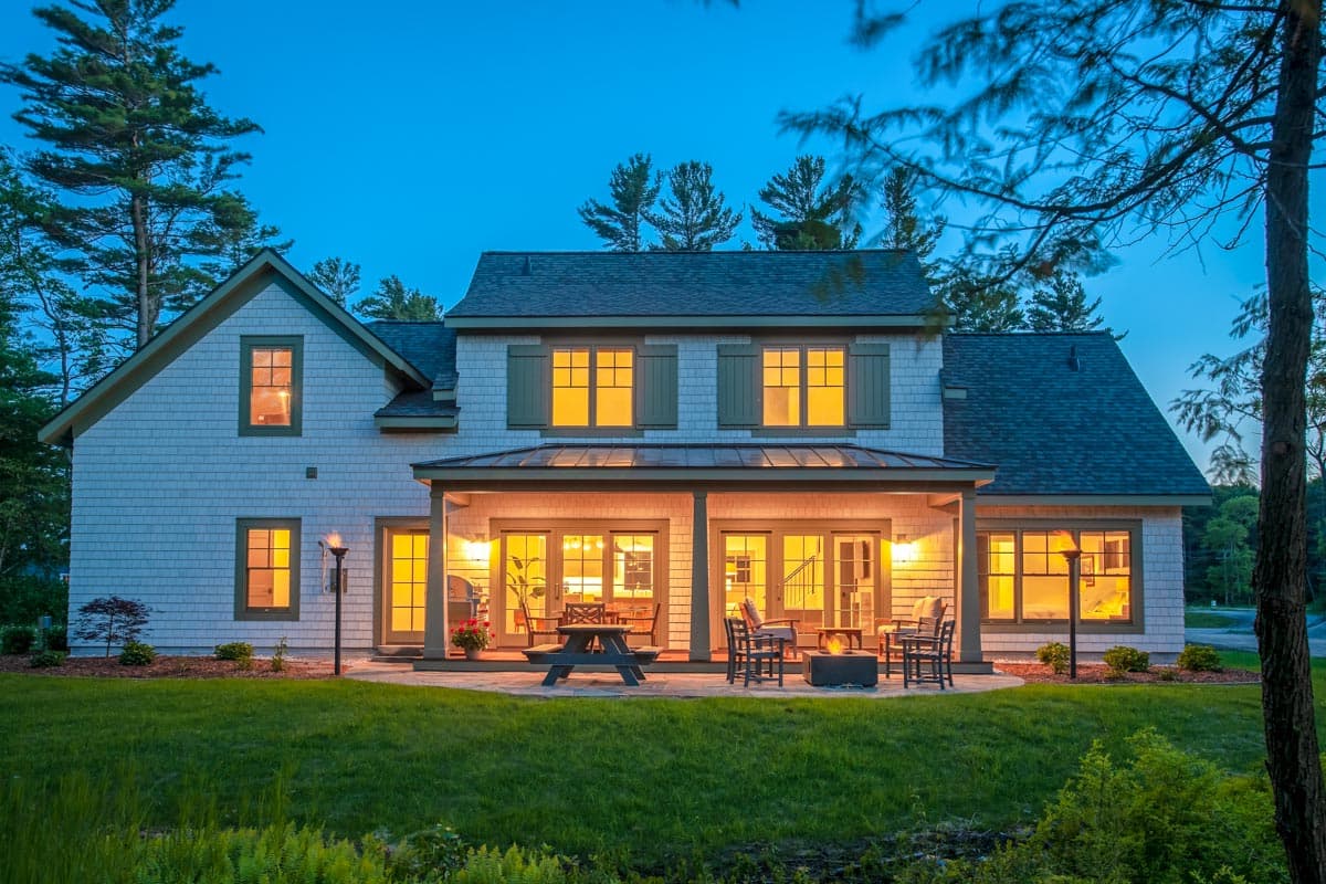 House plan exterior showing two-story Modern Farmhouse with gabled roof, cedar shingles, and covered patio with seating.