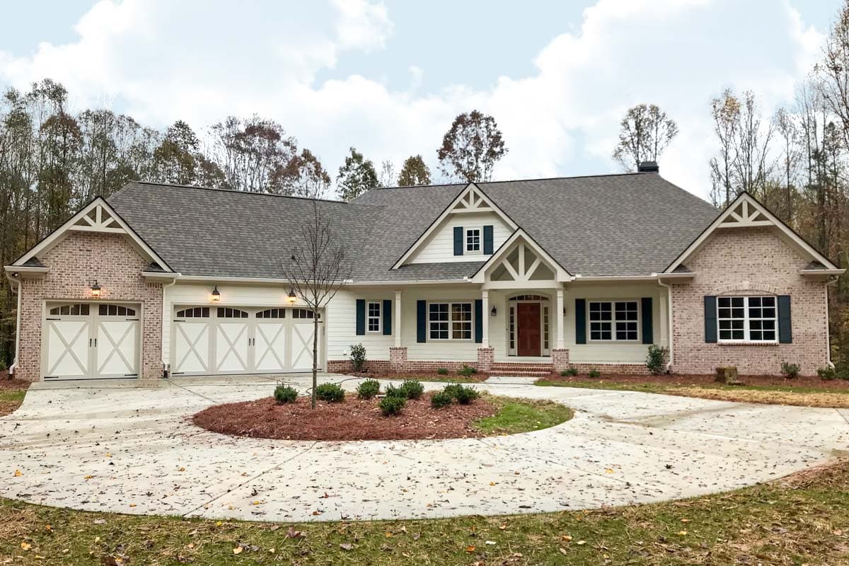 House plan exterior. Craftsman style, single story home with gables and a front porch. Features include a brick facade and attached garage.