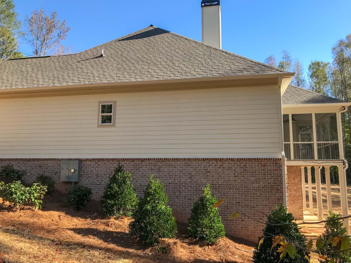 House plan exterior shows a two-story home with horizontal siding, brick lower level, gabled roof, and screened-in porch.