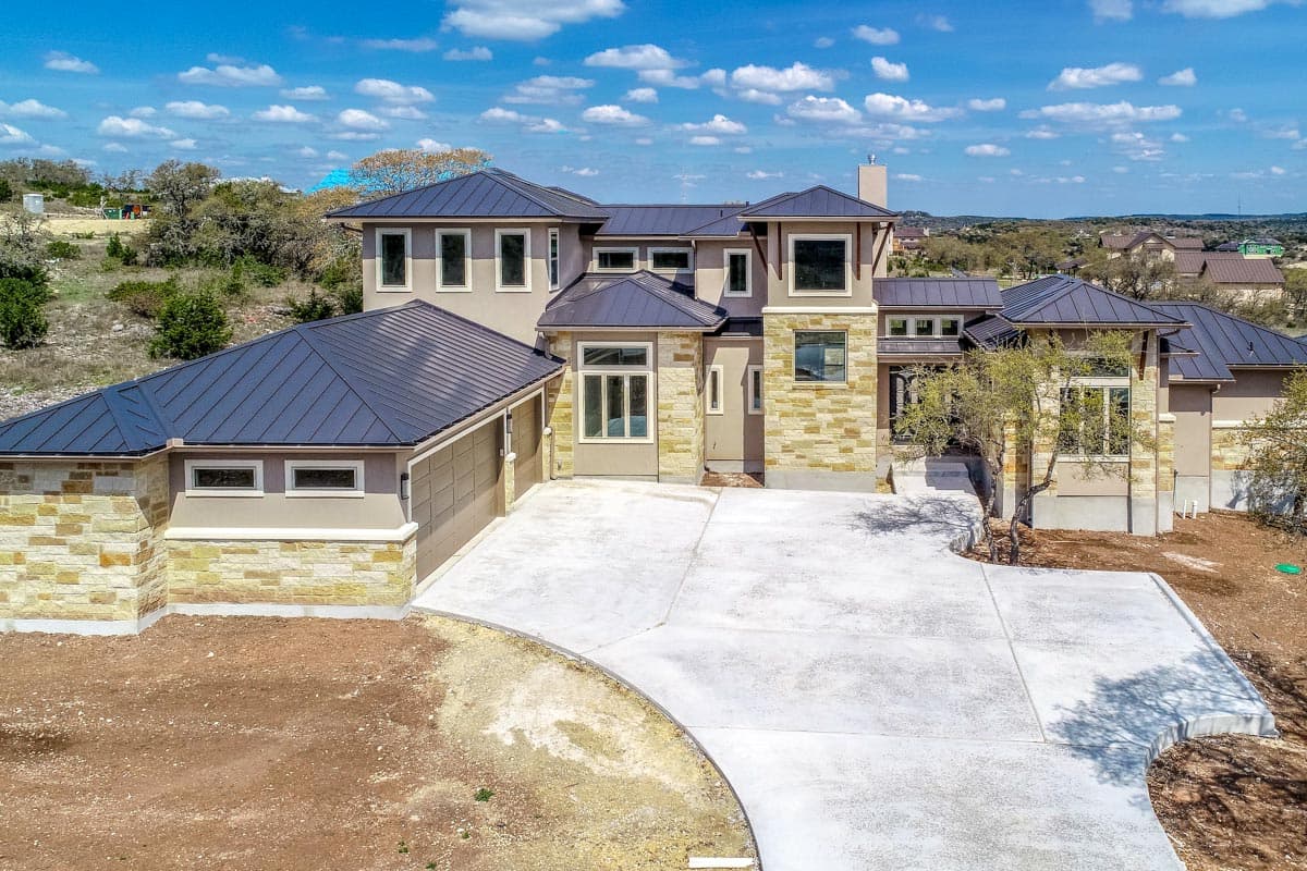 House plan exterior: Contemporary multi-story home with stone accents, metal roof, multiple gables, and attached garage.