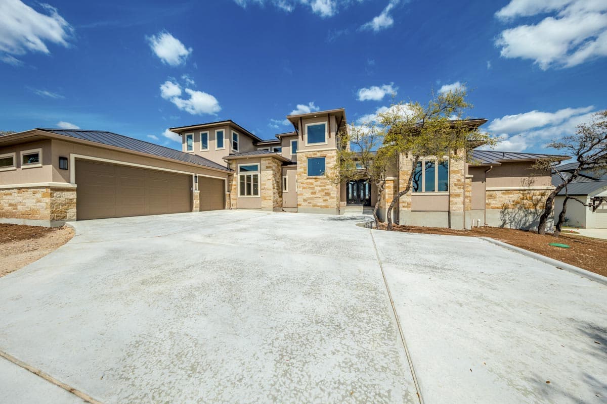 Modern house plan exterior with multi-level rooflines, stone accents, and a three-car garage.