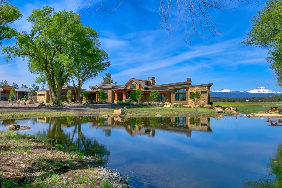 Modern ranch house plan exterior with a low-pitched roof, stone accents, expansive windows, and a covered entryway.