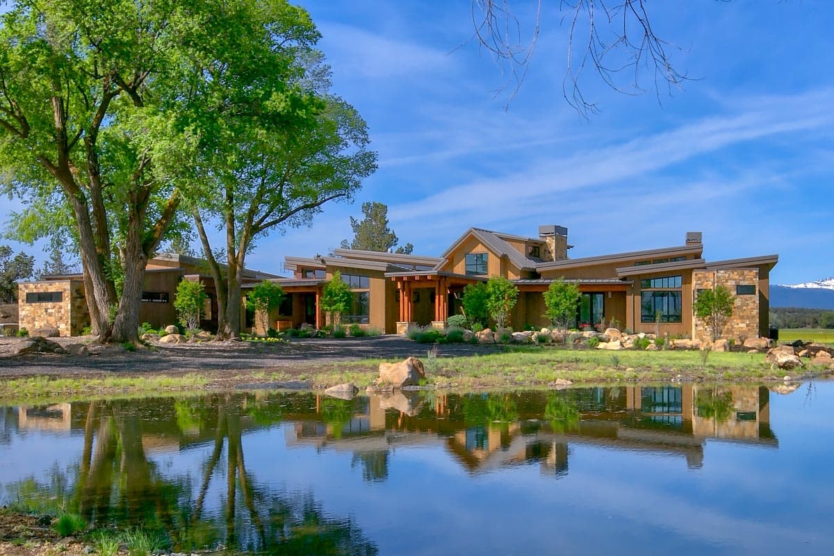 House plan exterior with modern style, one story, and flat and angled rooflines. Features stone accents, covered porch, and clerestory windows.
