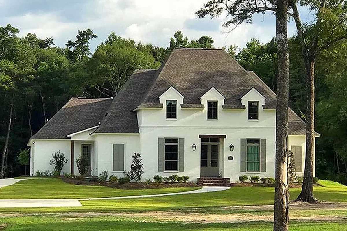 House plan exterior: two-story French Provincial style with brick facade, steeply pitched hipped roof, and dormer windows.
