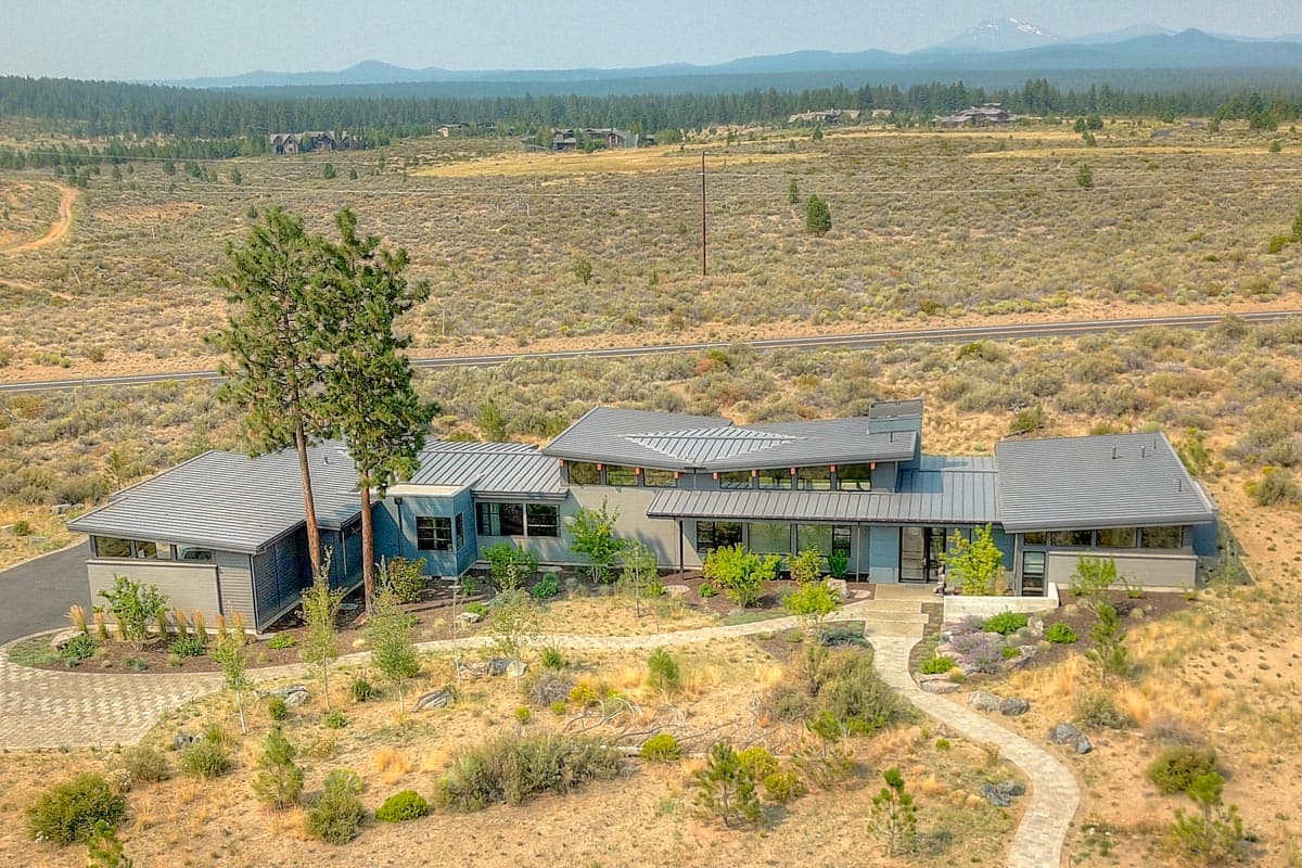 Modern house plan exterior with metal roof, multiple gables, large windows, and attached garage.