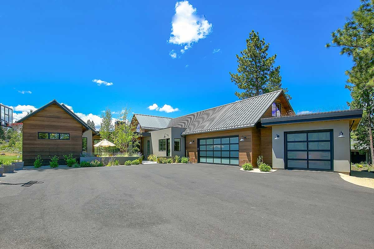 Modern house plan exterior with wood siding, metal roof, multiple gables, and two glass panel garage doors.