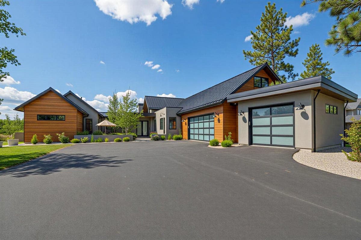 Modern house plan exterior with wood siding, metal roof, multiple gables, and glass garage doors.
