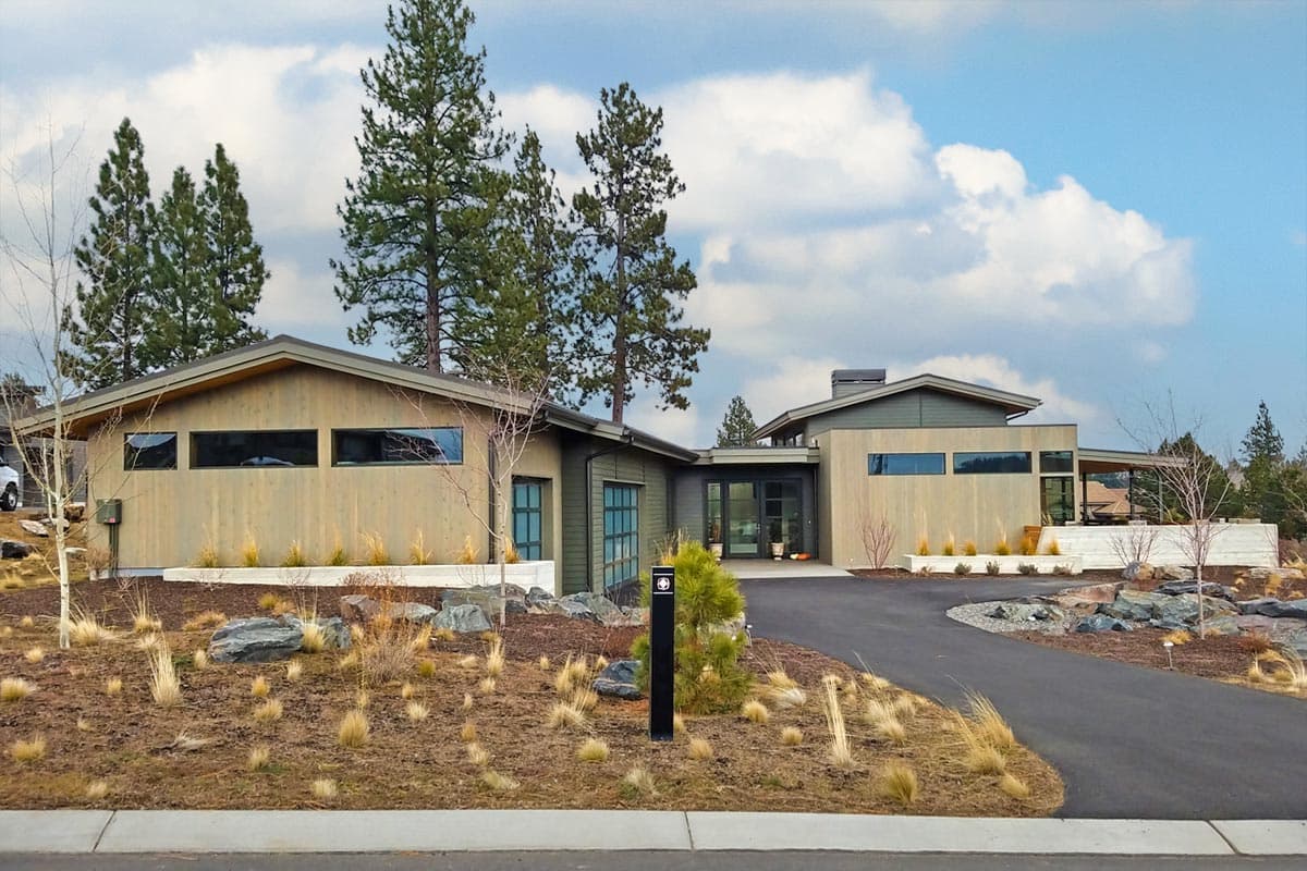 Modern house plan exterior with wood siding, multiple gables, a covered entryway, and a two-car garage.