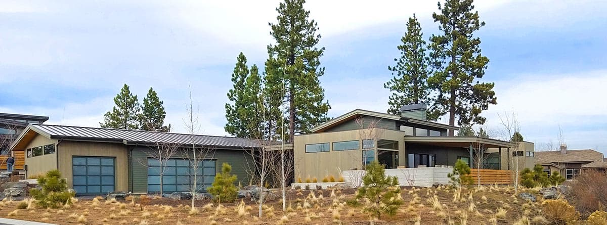 Modern house plan exterior with a long, low profile, metal roof, two glass garage doors, and cantilevered sections.