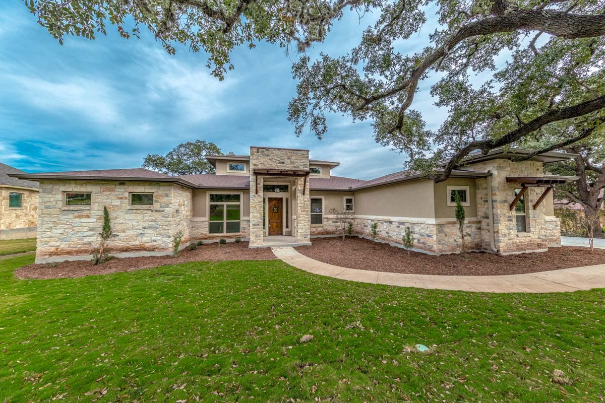 Modern style single-story house plan with stone accents, a covered entryway, flat rooflines, and large windows.