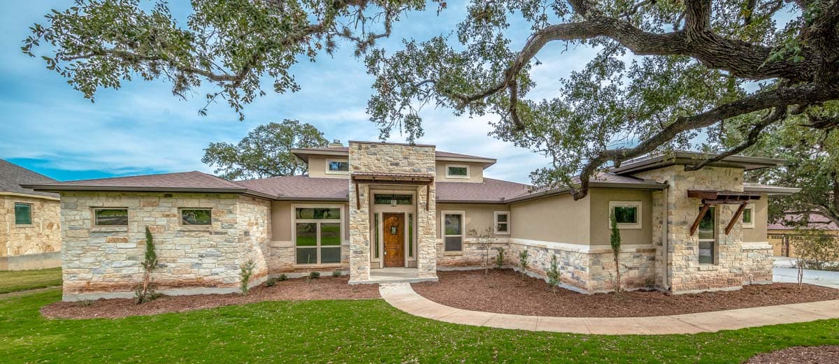 One-story house plan exterior with stone accents, a flat roof, prominent entry feature, and multiple recessed windows.