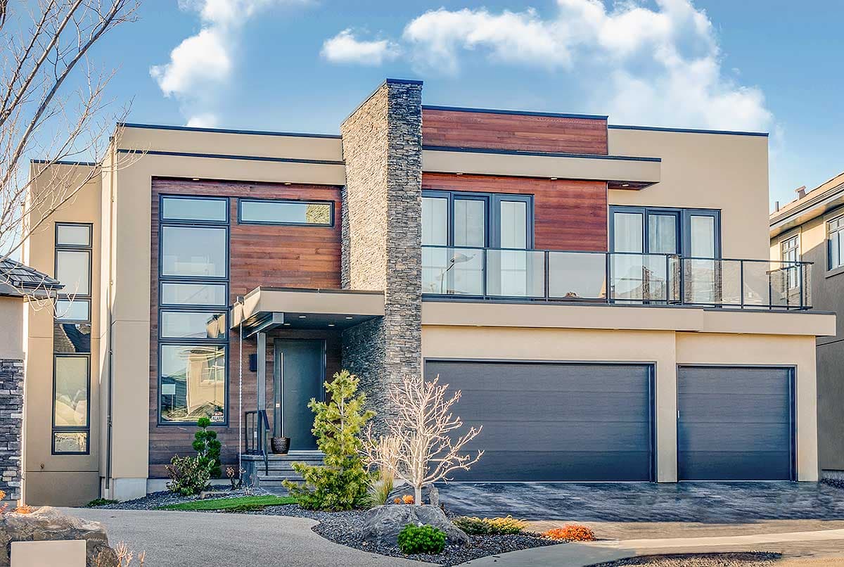 House plan exterior. Modern style, two-story home with wood siding accents, balcony with glass railing, and attached two-car garage.