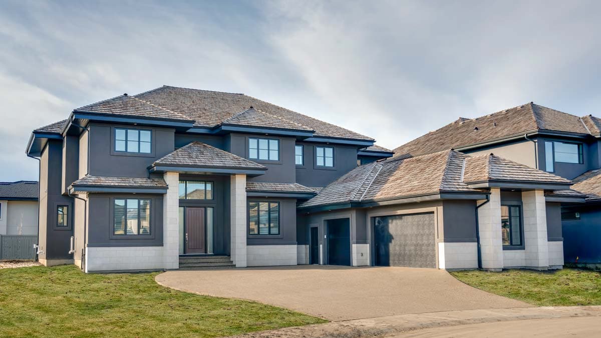 House plan exterior. Two-story home with a hipped roof and gabled entry. Features include a two-car garage and large windows.