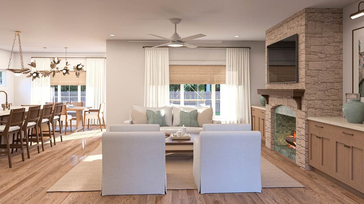 Open concept living area with a stone fireplace, built-in cabinetry, large windows, and dining area with chandelier.