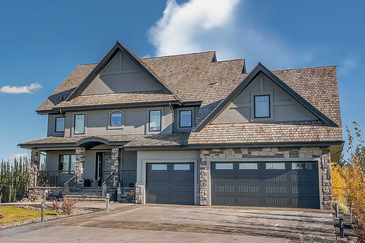 House plan exterior with stone accents, wood shake roof, two-story structure, and two gable roof dormers. Includes a front porch and two garage bays.