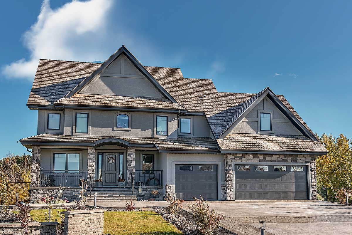 Two-story house plan exterior with stone accents, covered entry porch, and dual garage doors.