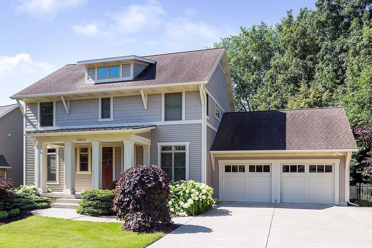 House plan exterior. Two-story home with a gabled roof, front porch with columns, and attached garage. Includes dormer and shingle siding.