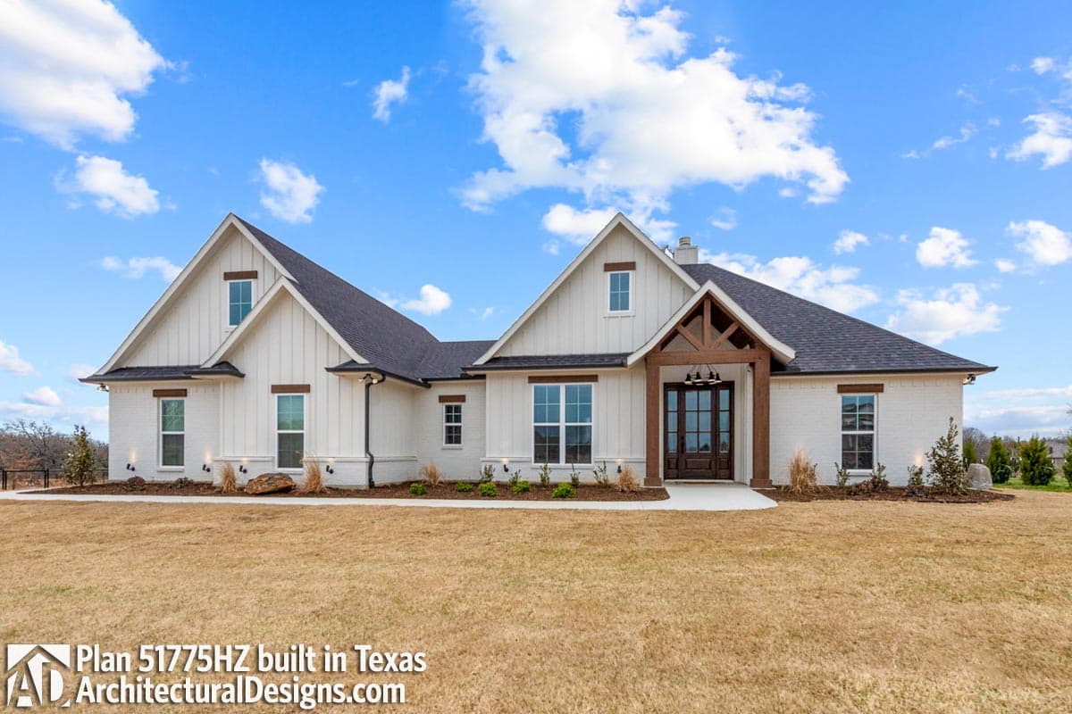 Modern Farmhouse style house plan exterior with white board-and-batten siding, brick base, gabled dormers, and timber-framed porch.