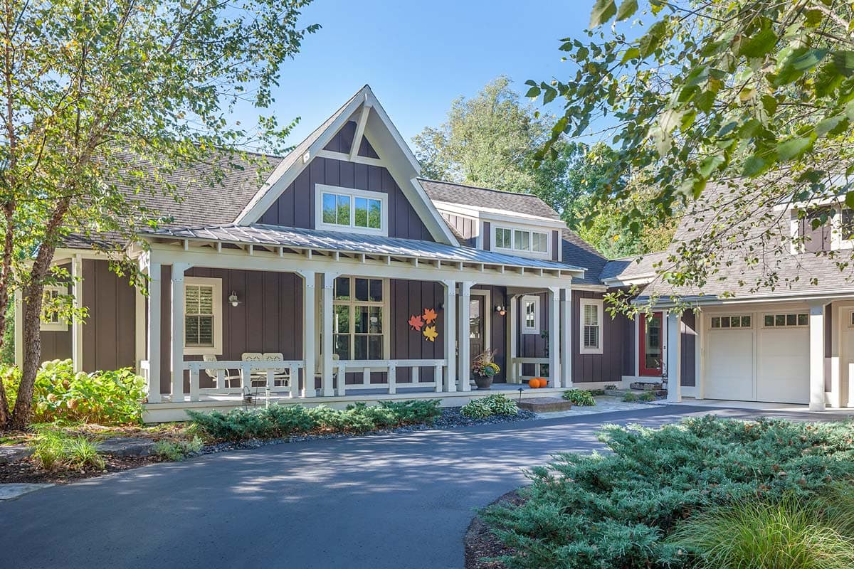 House plan exterior. Two-story Craftsman home with a gabled roof, covered porch, and attached garage. Includes dormers and vertical siding.