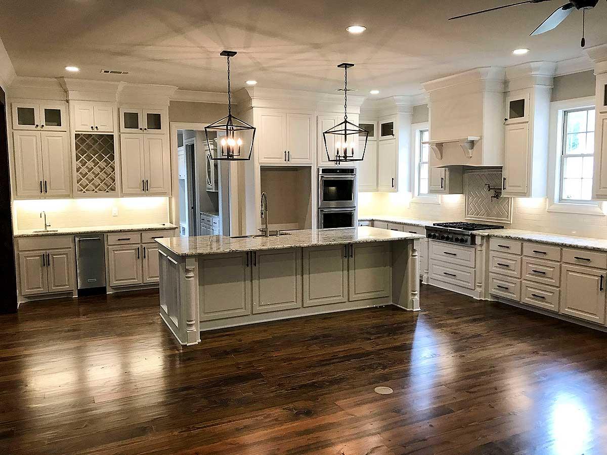 Spacious kitchen featuring a large island, dual ovens, gas range, wine rack, and pendant lighting.