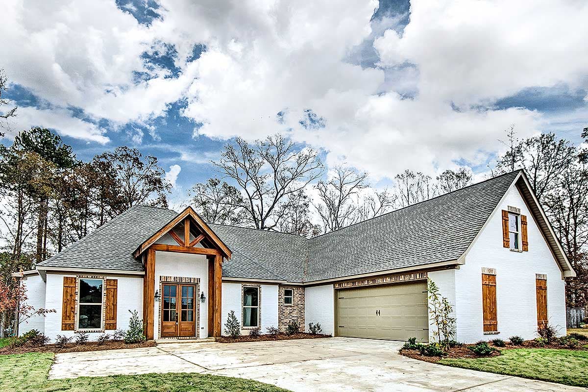 House plan exterior. Ranch style with a gabled roof, exposed wood beams, and a two-car garage. Features include wood shutters and a front entry.