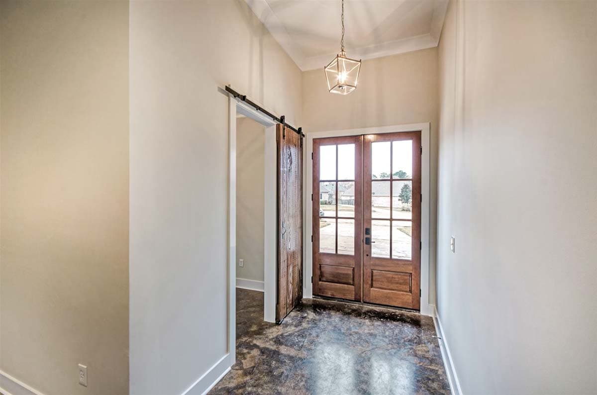 Interior view of entryway with double glass doors, a sliding barn door, and a geometric pendant light.