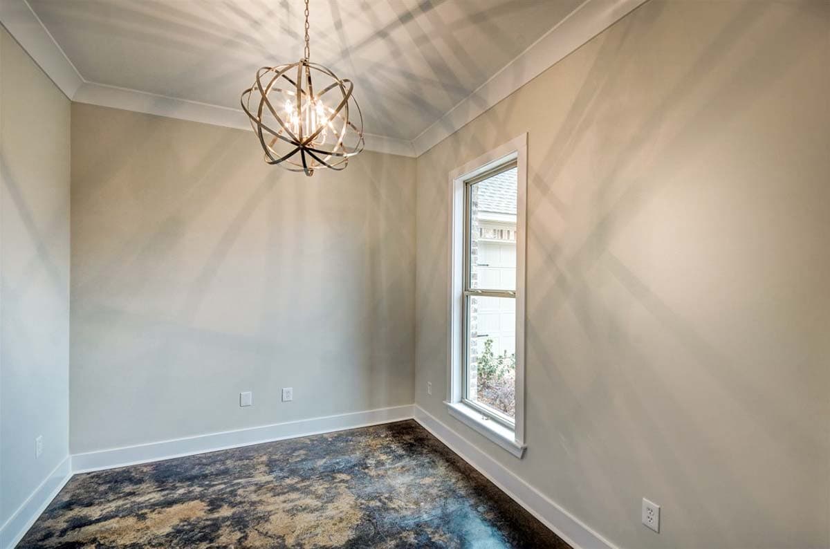 Interior view of a room with a large window, decorative chandelier, and stained concrete floor.
