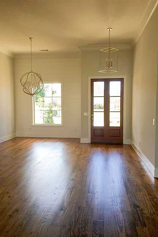 Interior view of a room with hardwood floors, shiplap accent wall, large window, and double-door entry.