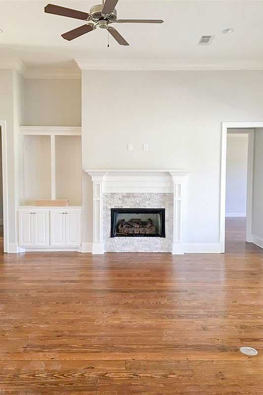 Interior view of a living room featuring a gas fireplace with marble surround and built-in shelving.