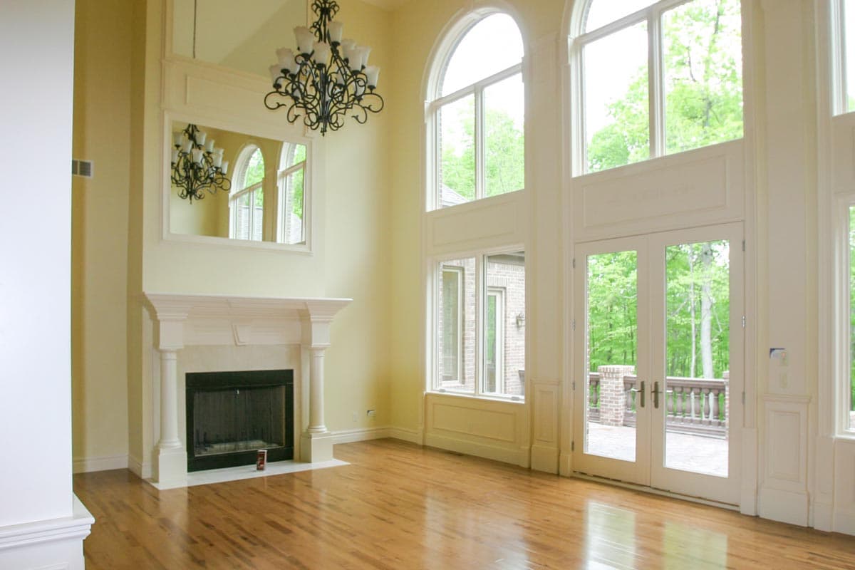 Great room with a fireplace, tall arched windows, and French doors leading to an outdoor patio.