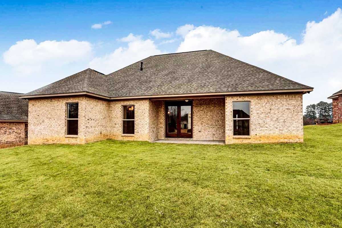 One-story brick house plan exterior with a hip roof, covered back patio, and multiple windows.