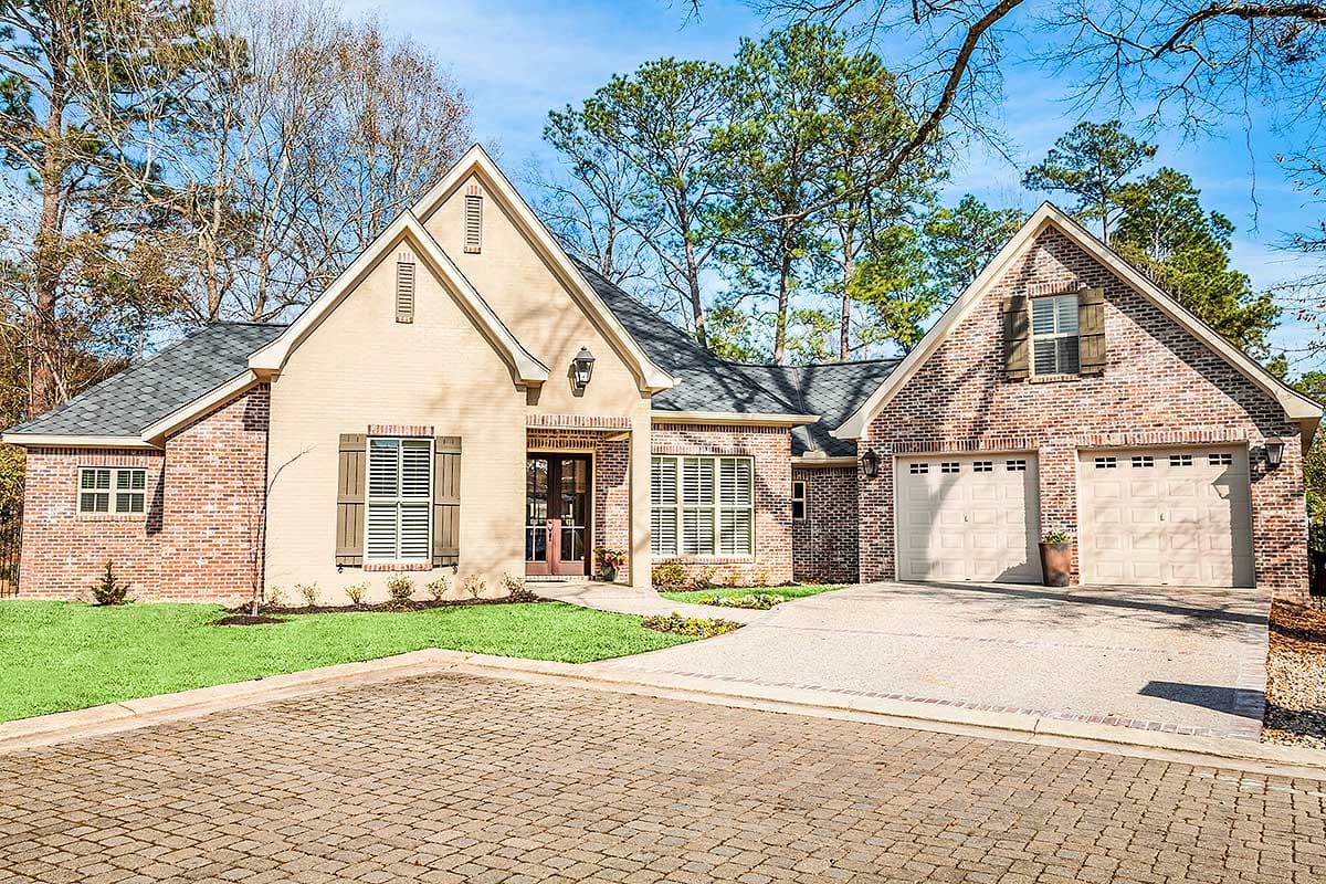 House plan exterior. Two-story, brick and stucco facade with gabled rooflines, decorative shutters, and attached two-car garage.