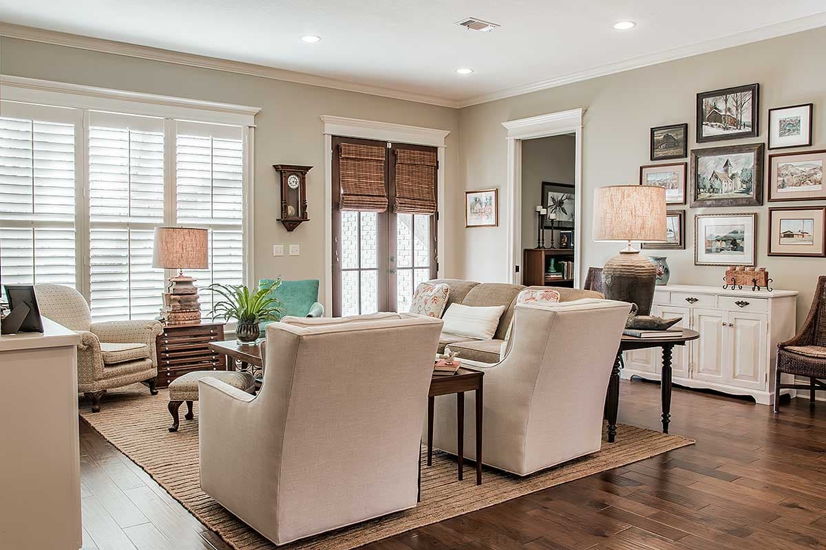 Interior view of a living room with plantation shutters, French doors, sofa, chairs, and artwork.