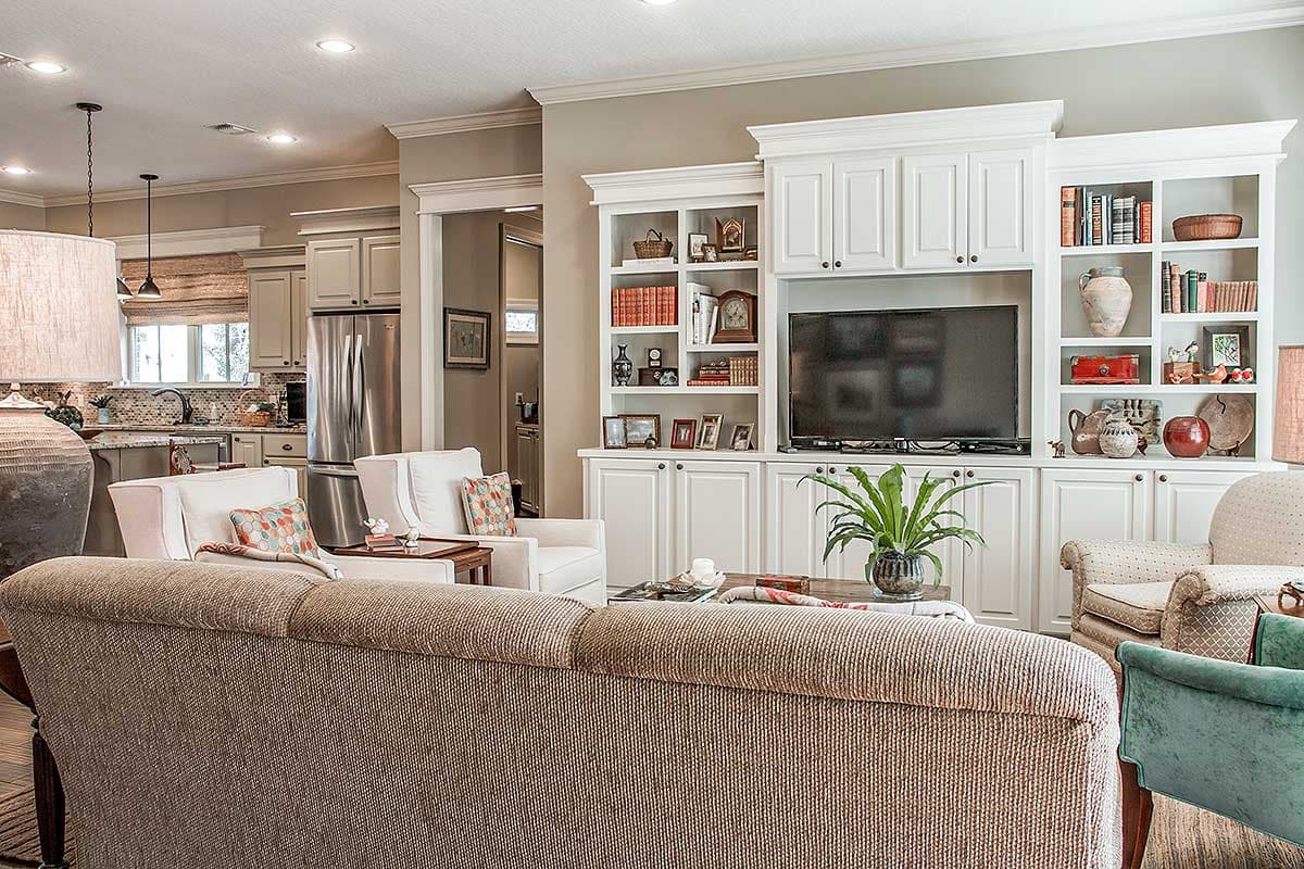 Great room with built-in shelving, television, fireplace, and view of kitchen with stainless steel appliances.