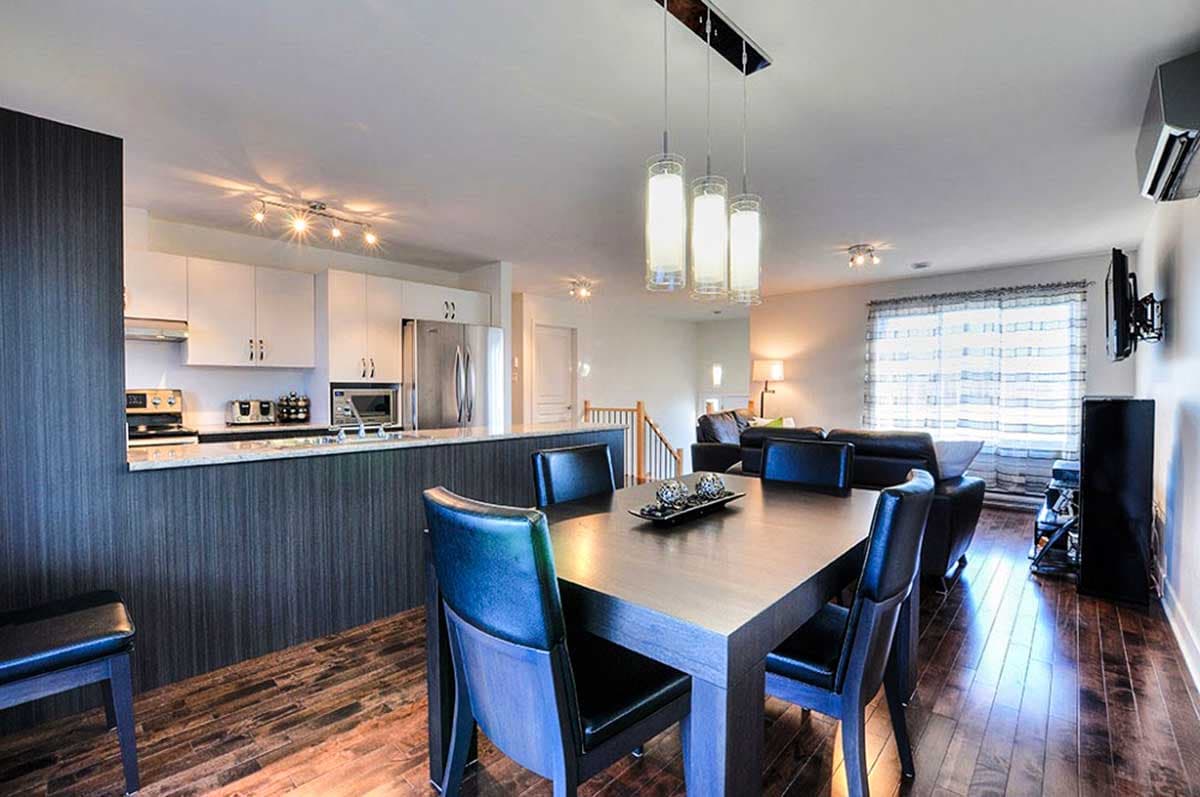 Open-concept interior with modern kitchen, dining area, and living room. Features include a kitchen island, pendant lights, and hardwood floors.