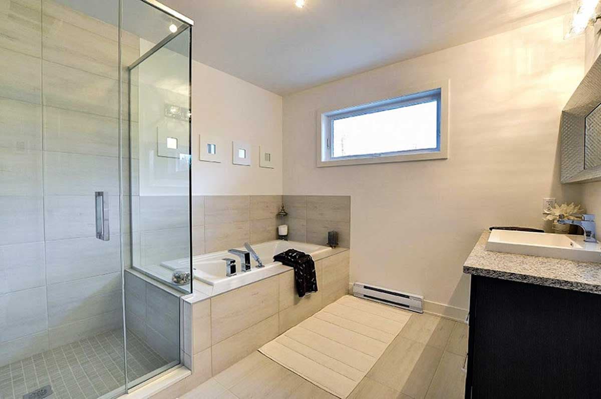 Bathroom with glass-enclosed shower, soaking tub, vanity with sink, and horizontal window.