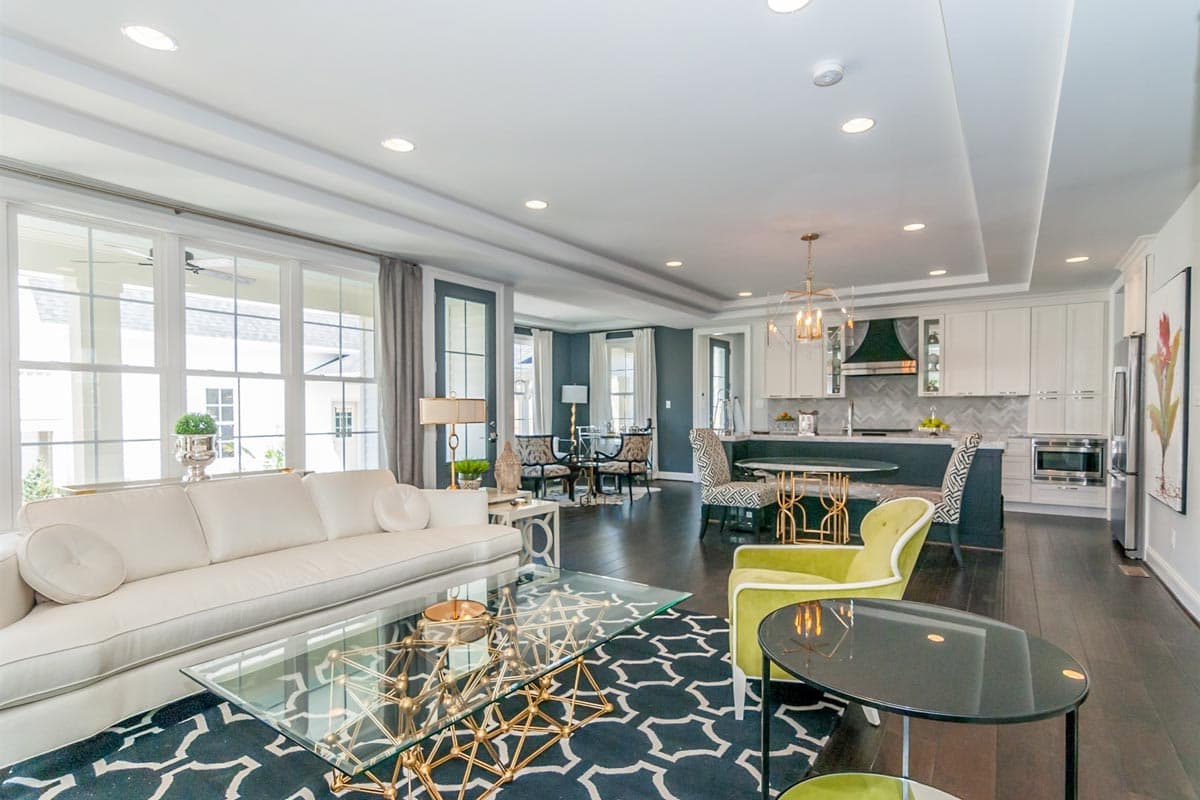 Interior rendering of an open-concept living area with a sectional sofa, kitchen island, and dining space.