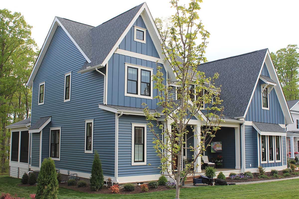 Two-story blue house plan with gables, white trim, multiple dormers, and a covered front porch.