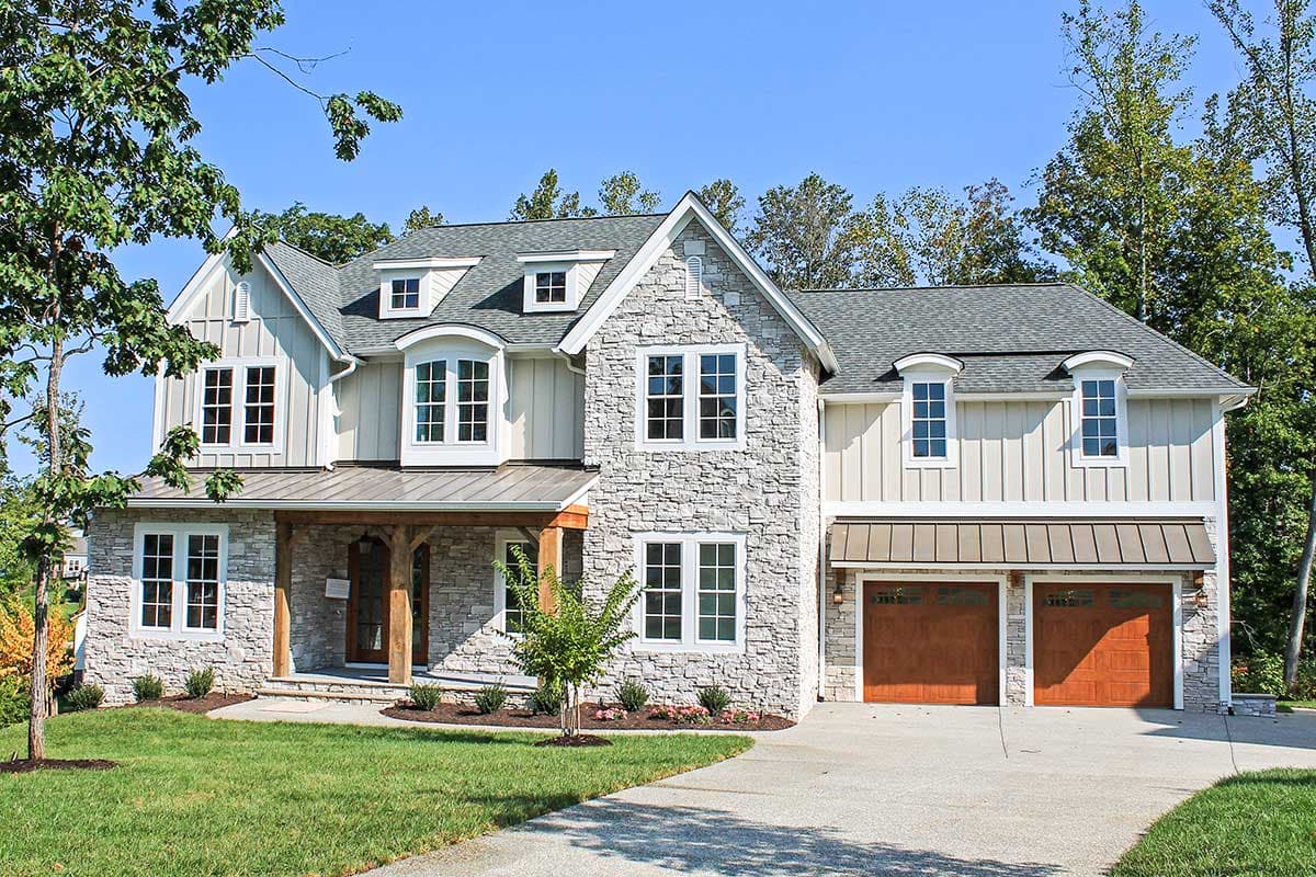 House plan exterior. Two-story, Craftsman-style home with stone and siding facade, covered porch, dormers, and attached garage.