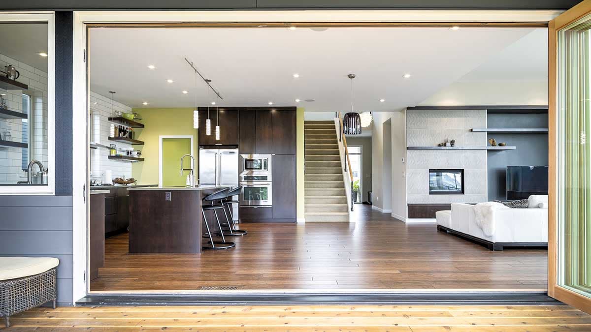 Open concept living area with kitchen island, stainless steel appliances, fireplace, and staircase.