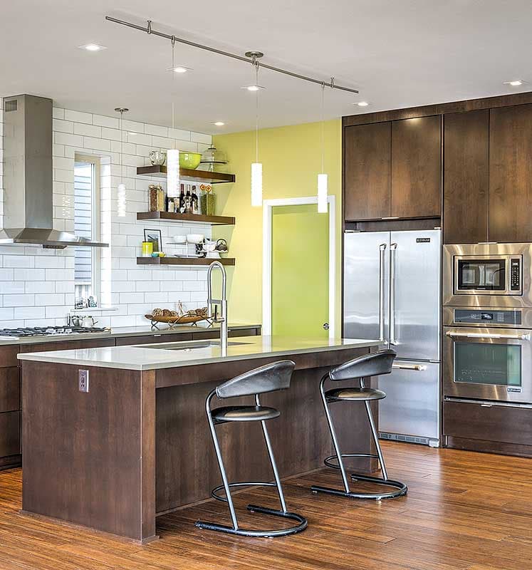 Kitchen with island, stainless steel appliances, subway tile backsplash, and dark wood cabinetry.