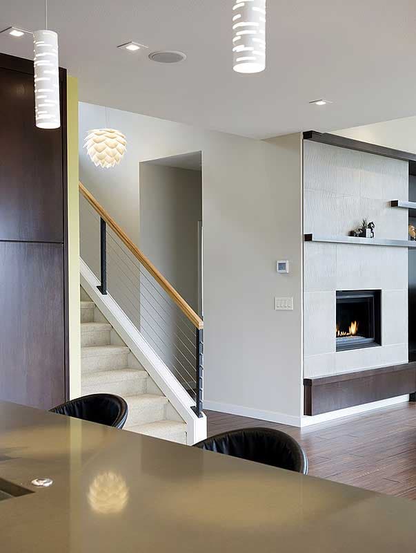 Modern interior view showing a carpeted staircase, fireplace with tile surround, and pendant lighting.