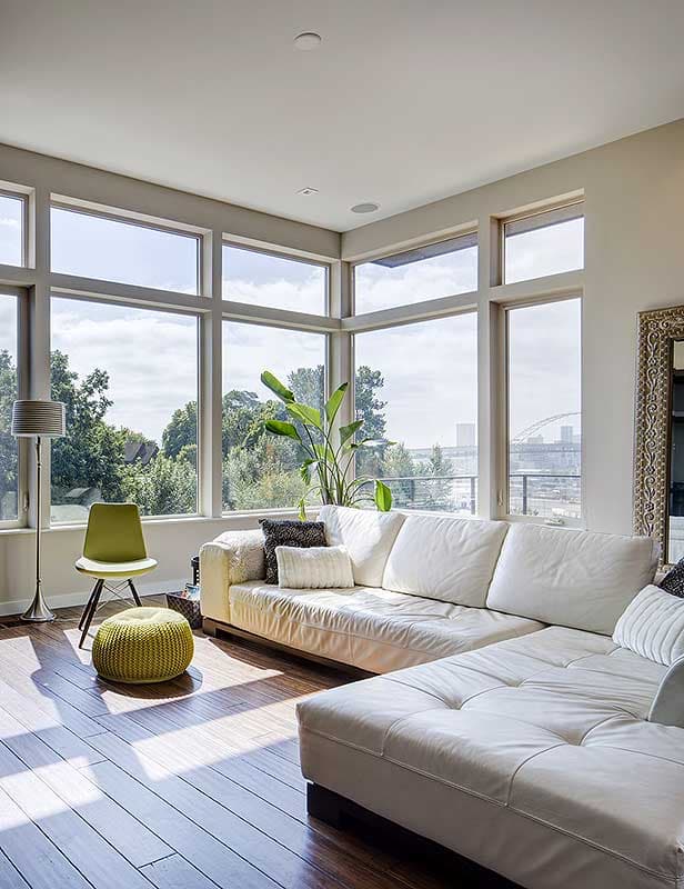 Living room with sectional sofa, large corner windows, and hardwood floors.
