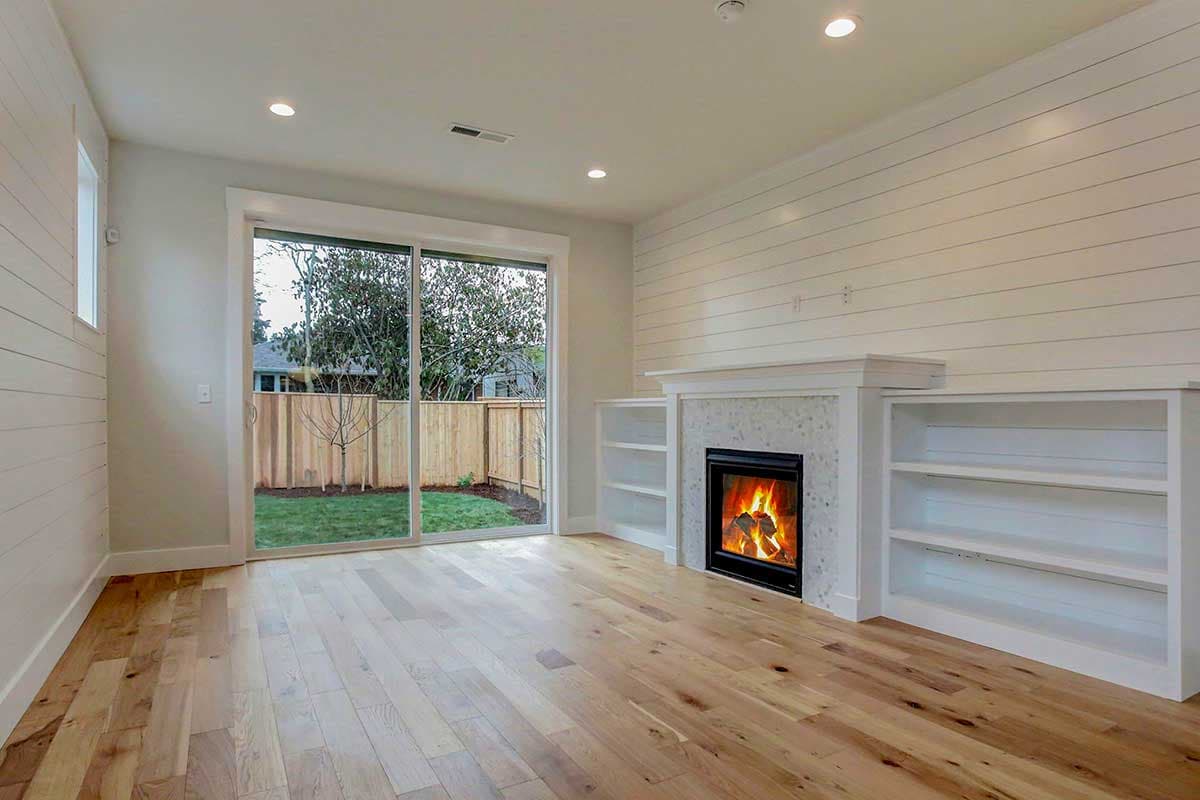 Living room with fireplace, built-in bookshelves, shiplap accent wall, and sliding glass door to backyard.