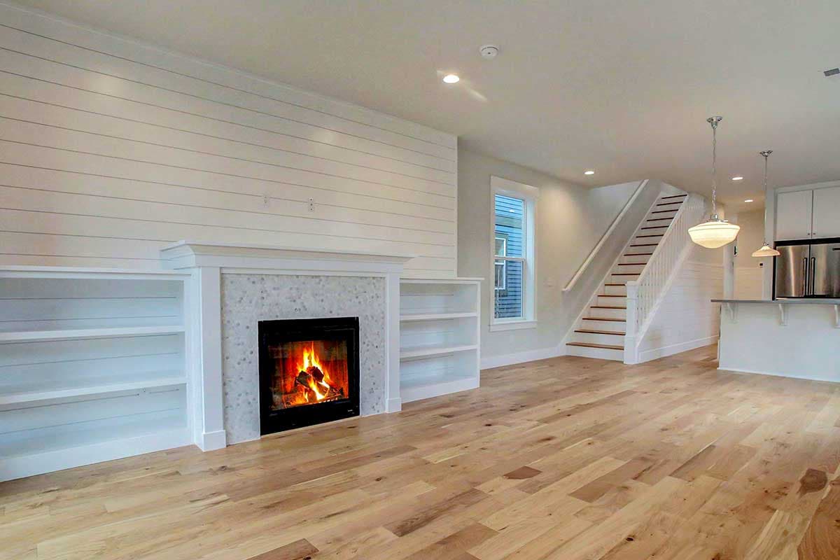 Interior view of living area with fireplace, built-in bookshelves, and open staircase to second floor.