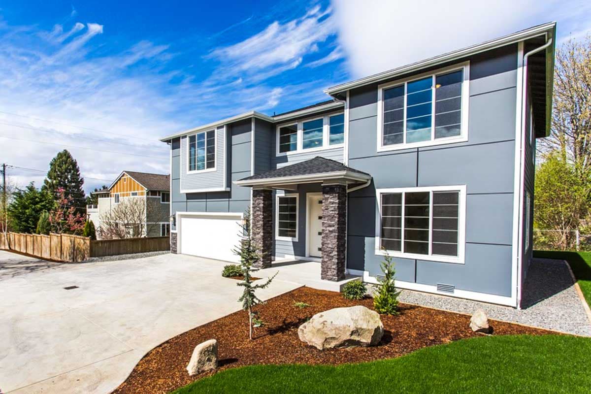 Modern two-story house plan exterior with layered siding, covered entry with stone pillars, and attached garage.