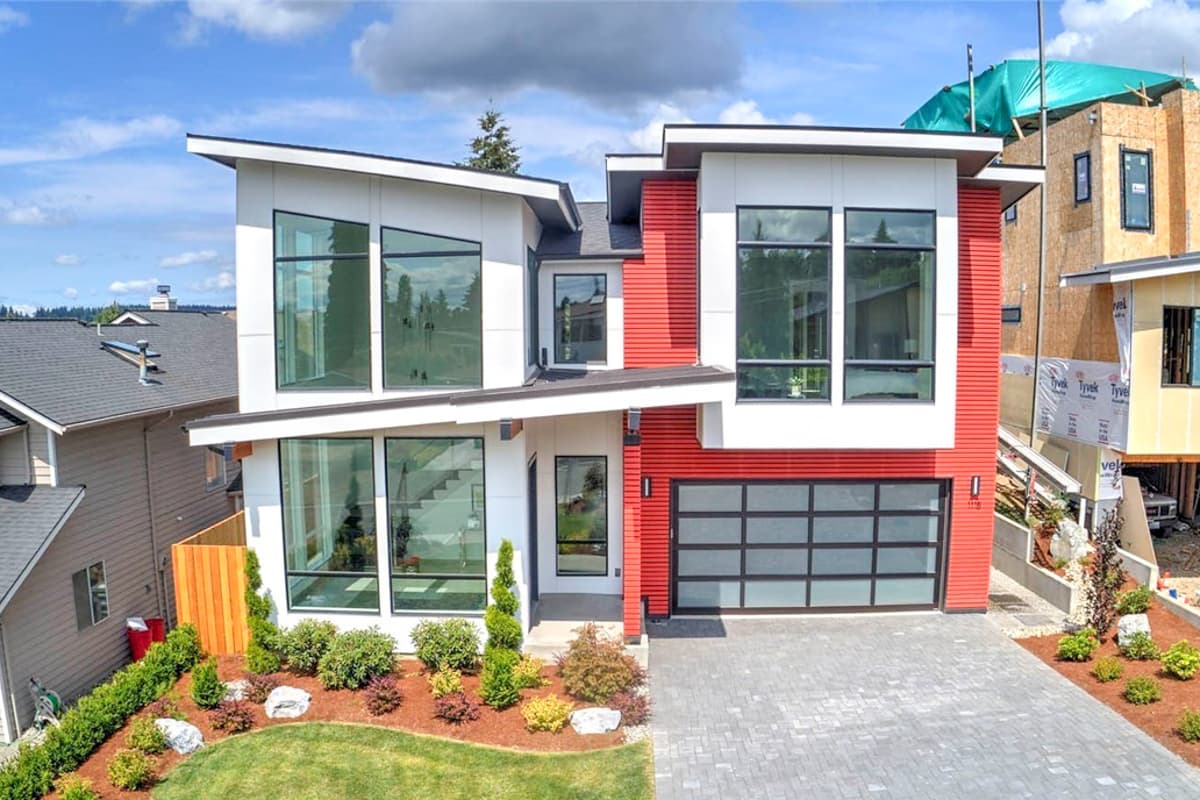 Modern two-story house plan exterior with angled rooflines, large geometric windows, a red accent facade, and a glass garage door.
