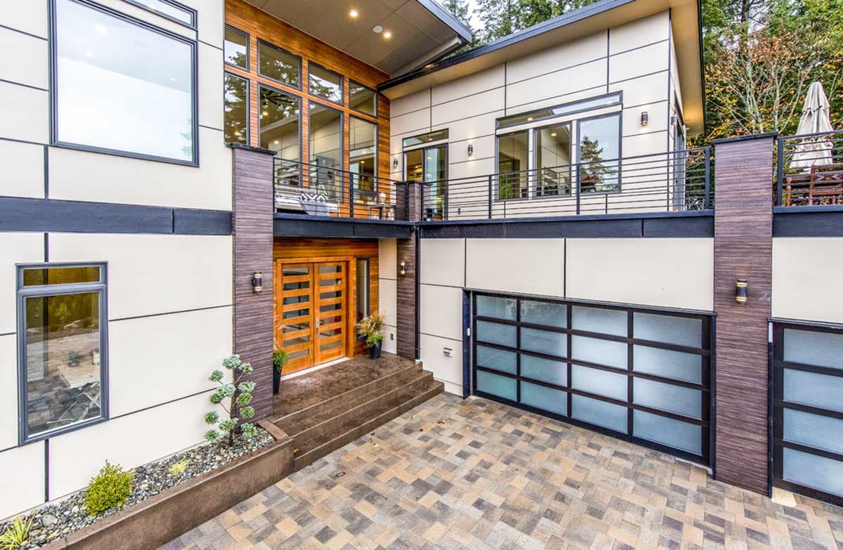 Modern house plan exterior with a two-story facade, wood double front doors, large glass garage door, and balcony.