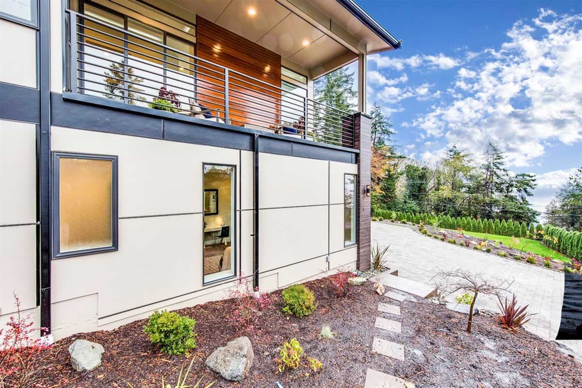 Modern house plan exterior with a balcony, horizontal siding, and large windows.