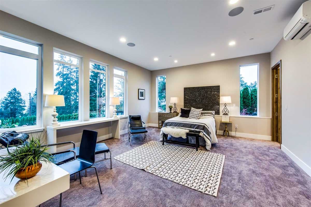 Primary bedroom with large windows, king bed, seating area, and patterned rug.
